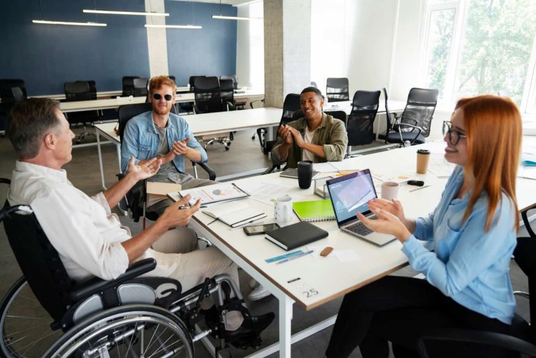 Diverse group of employees, including a man using a wheelchair, collaborating in a modern Vancouver office, representing inclusive employment and job coaching.